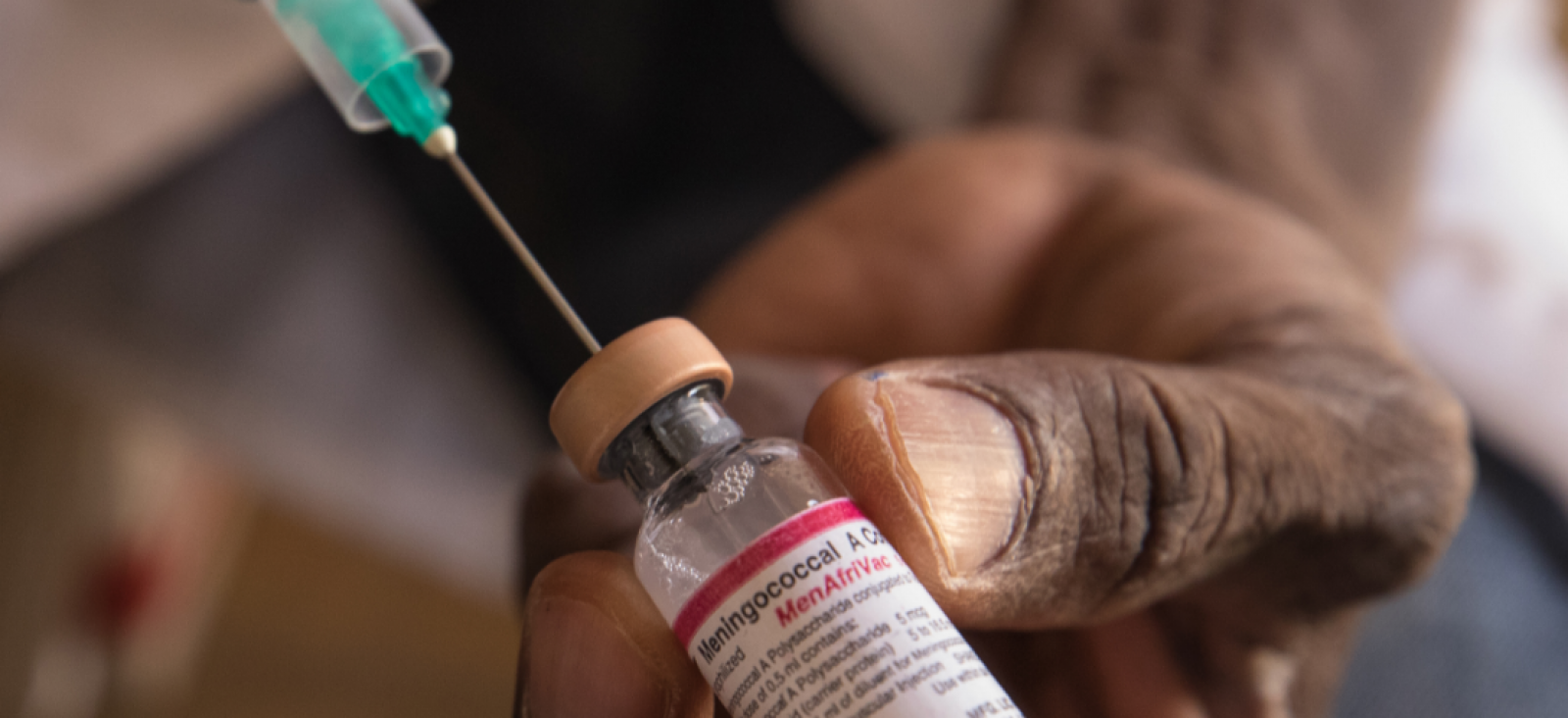 Syringe is inserted into a vial of the MenAfriVac vaccine.